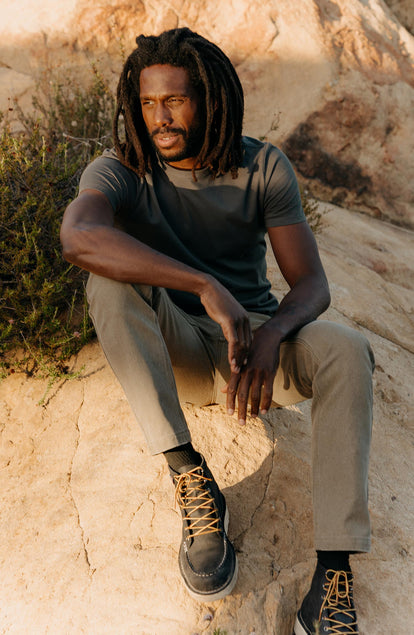 fit model sitting on a rock wearing The Organic Cotton Tee in Faded Black