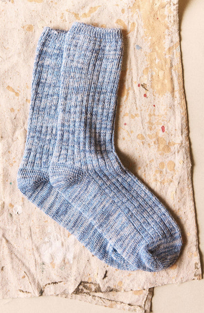 The Ribbed Sock in Blue Melange on a textured surface