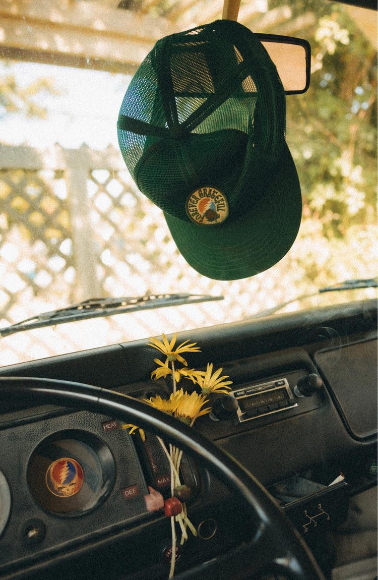 editorial image of The 6-Panel Trucker Cap in Emerald Mesh on a rearview mirror