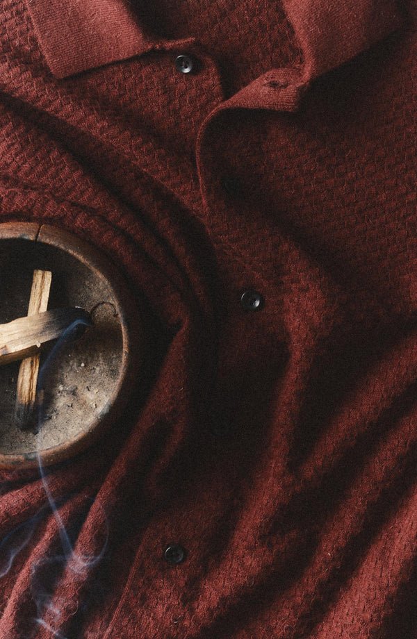 editorial flatlay of The Arlo Sweater Polo in Burgundy Texture Knit with palo santo