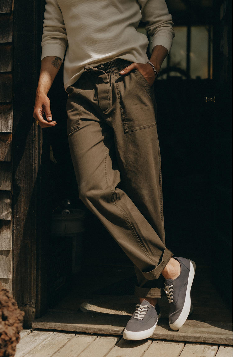 fit model leaning against the wall wearing The Breakwater Pant in Mushroom Ripstop