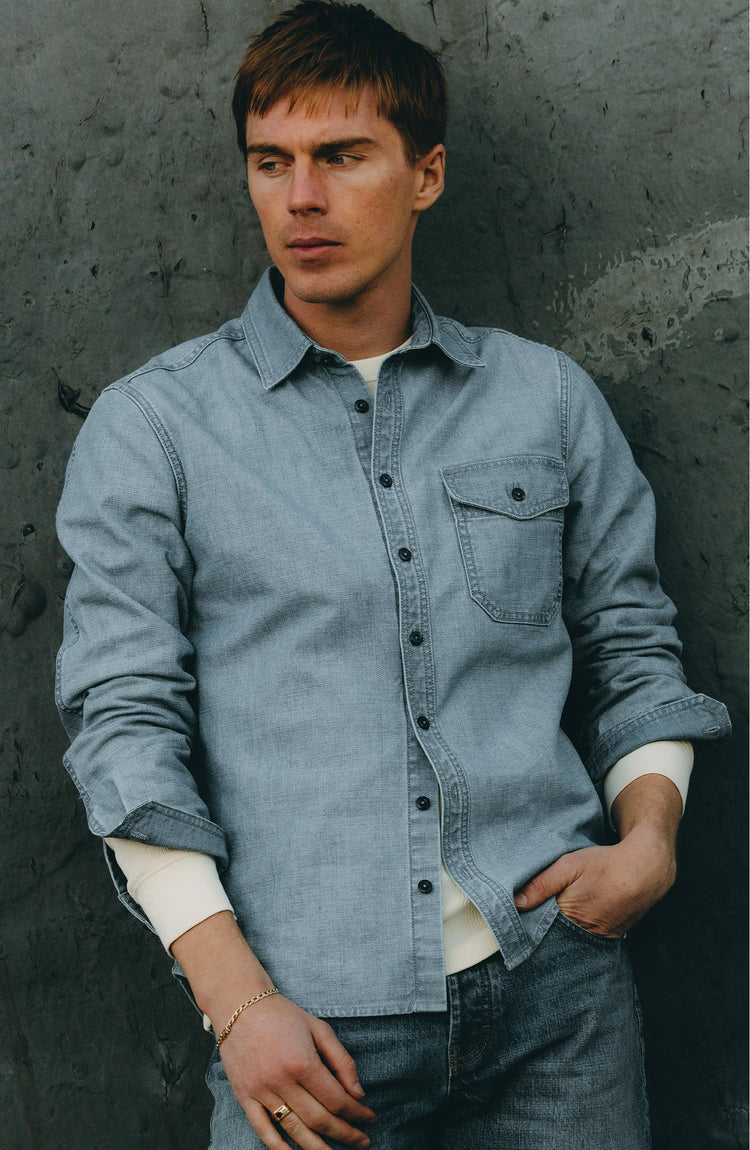 fit model leaning against the wall wearing The Cadet Shirt in Washed Indigo Oxford