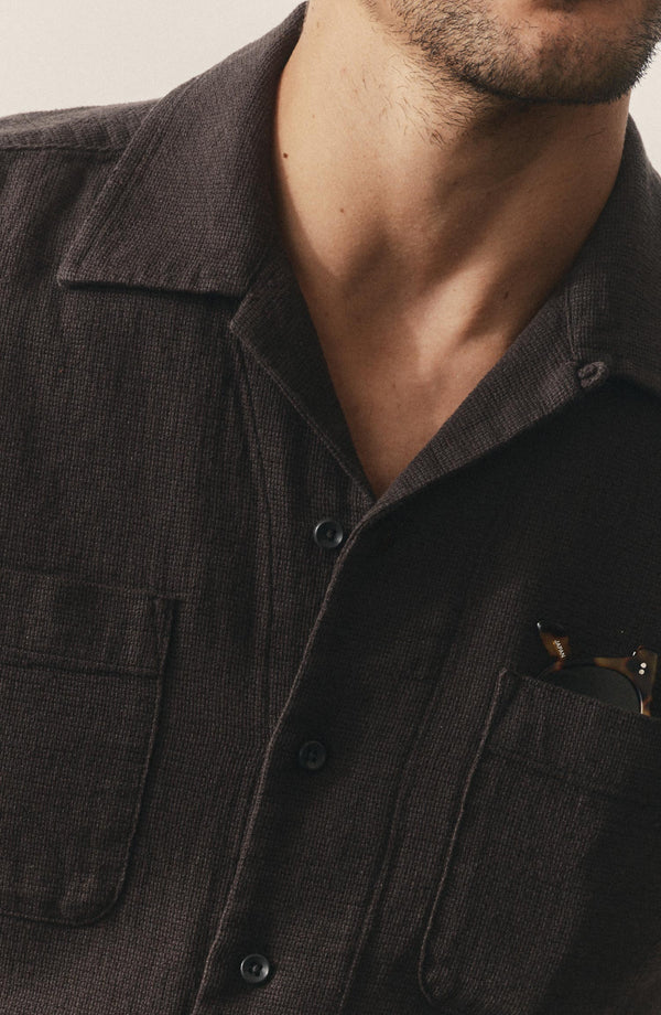 editorial image of The Conrad Shirt in Faded Black Linen hanging on a painting