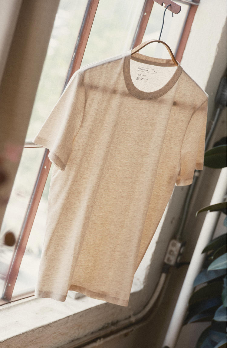editorial image of The Cotton Hemp Tee in Heather Oat hanging in a window