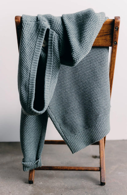 editorial image of The Crawford Sweater Hoodie in Deep Sea Twist on a chair 