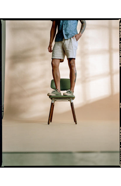 fit model standing on a chair wearing The Easy Short in Natural Linen