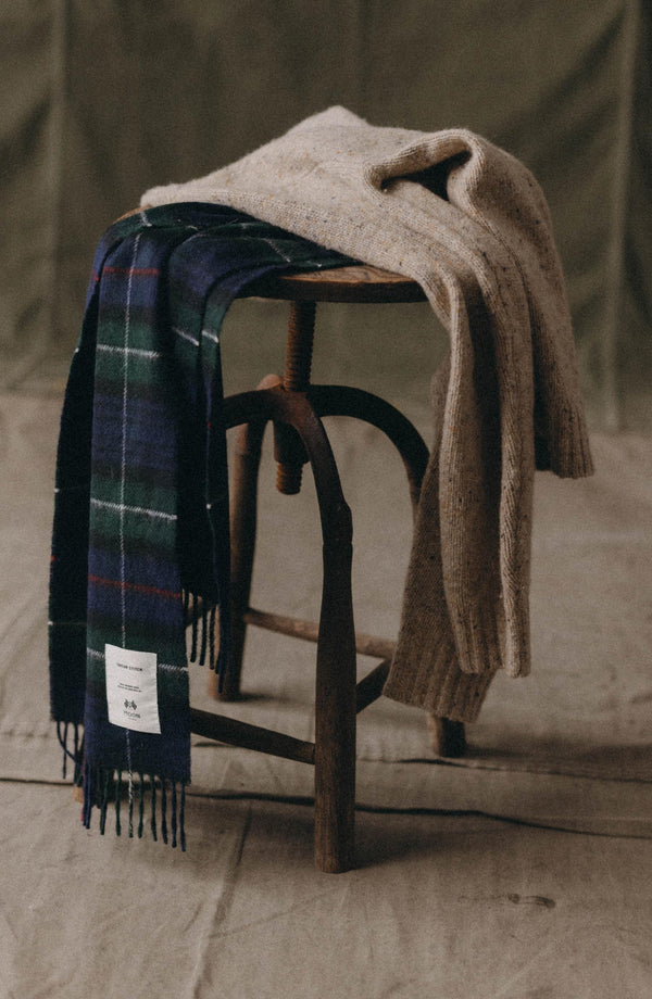 editorial image of The Fireside Scarf in Highland Navy Plaid on a stool