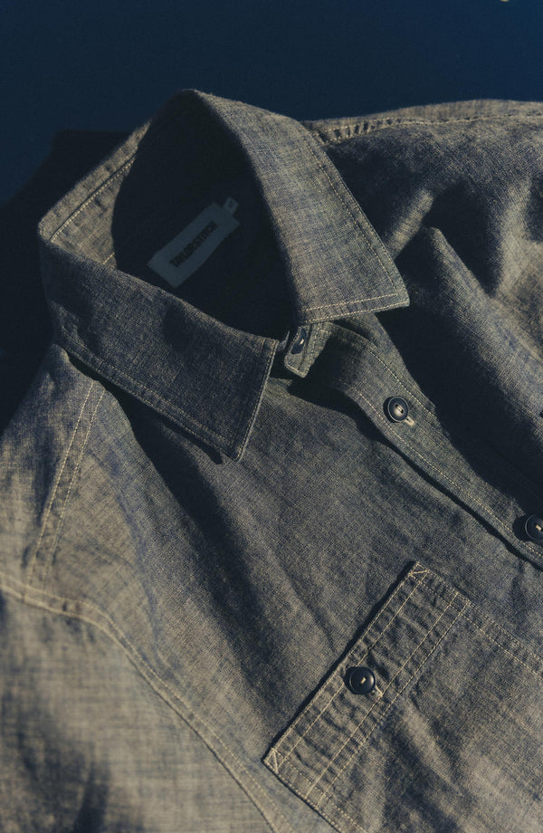 fit model sitting wearing The Foundry Shirt in Rinsed Indigo Chambray