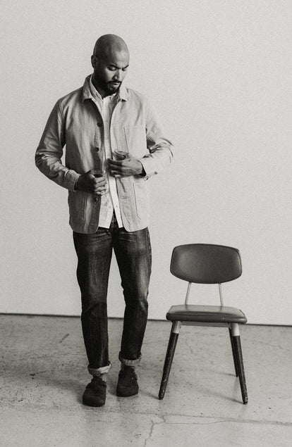 fit model standing next to a chair wearing The Ojai Jacket in Organic Light Khaki Foundation Twill