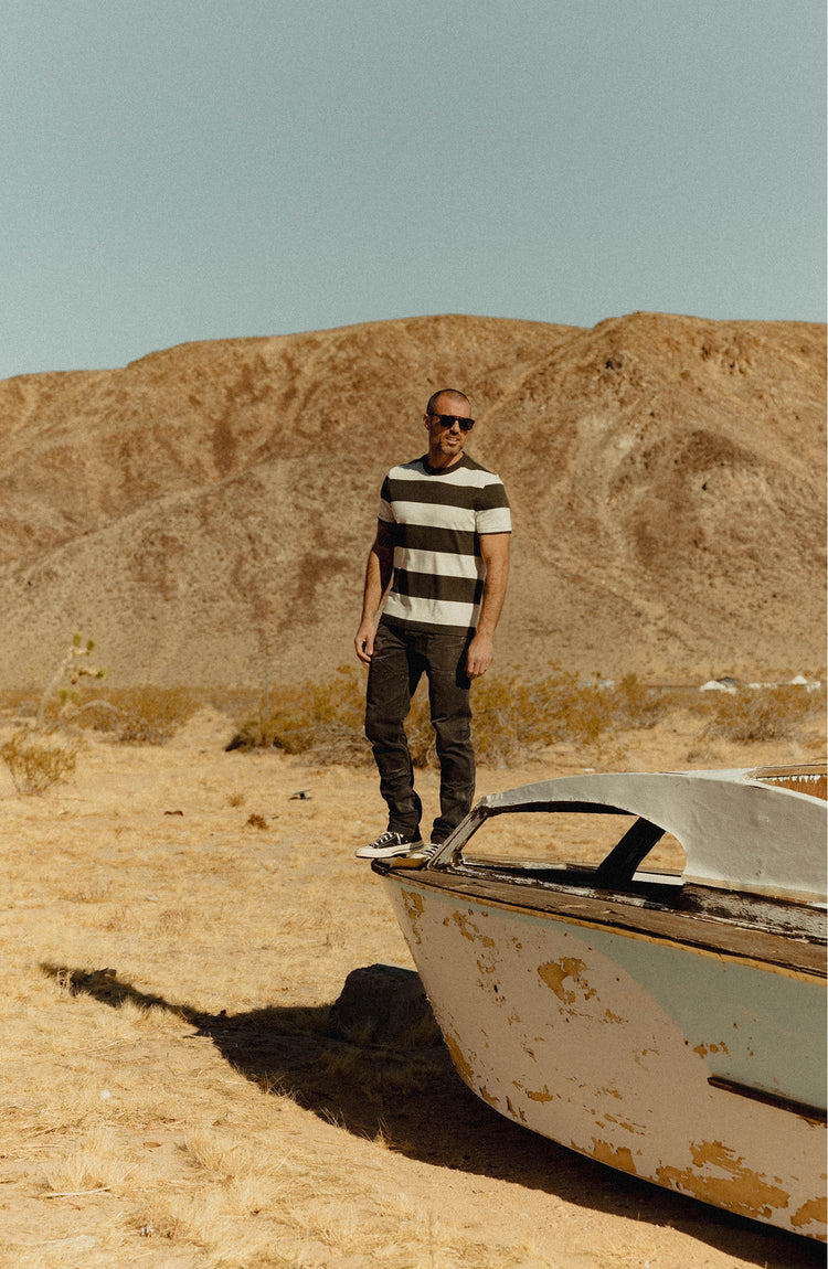 fit model standing on a boat wearing The Organic Cotton Shop Tee in Faded Black Stripe