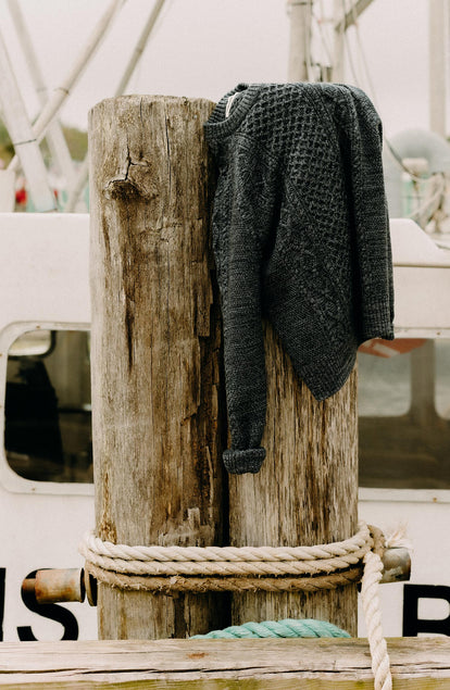 editorial image of The Orr Sweater in Marled Marine Merino on a log