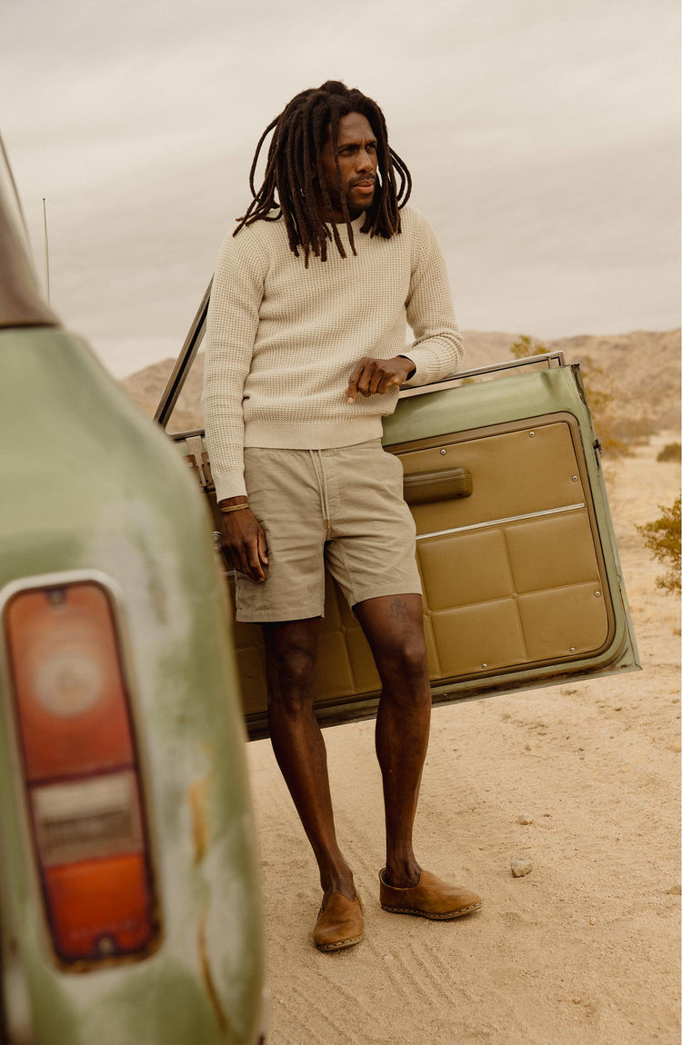 fit model leaning against a car wearing The Ranger Sweater in Heather Fog Linen Waffle