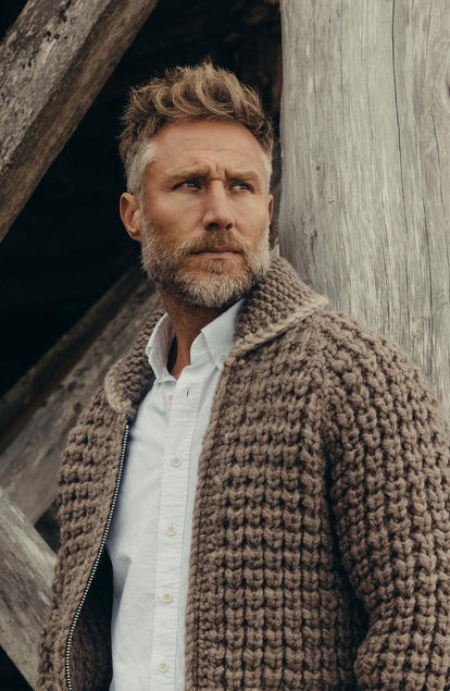 fit model leaning against a pole wearing The Seawall Hand-Knit Sweater in Heather Sable