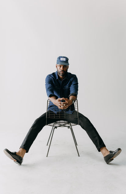 fit model sitting wearing The Slim Jean in Rigid Black Organic Selvedge
