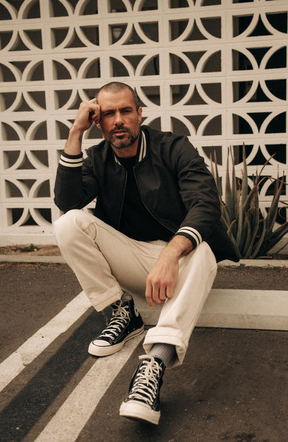 fit model sitting wearing The Speedway Bomber in Organic Faded Black Twill