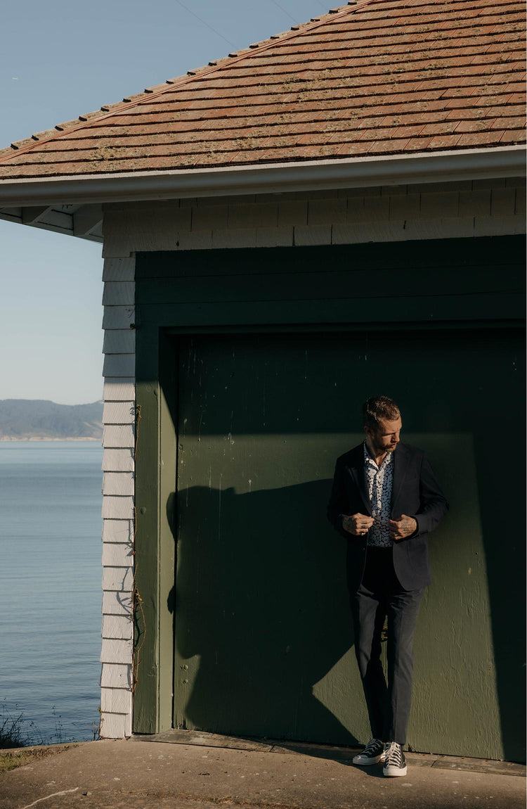 fit model leaning against the wall wearing The Stevens Sportcoat in Navy Linen Seersucker