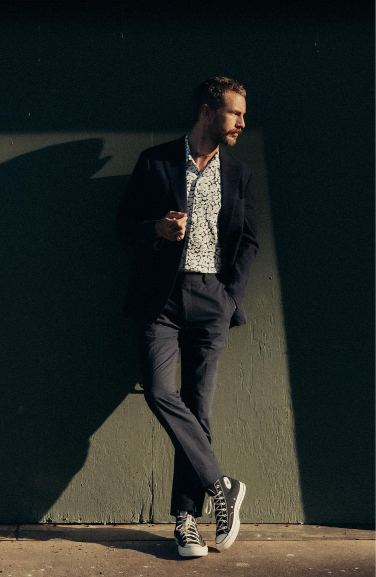 fit model leaning against the wall wearing The Stevens Trouser in Navy Linen Seersucker