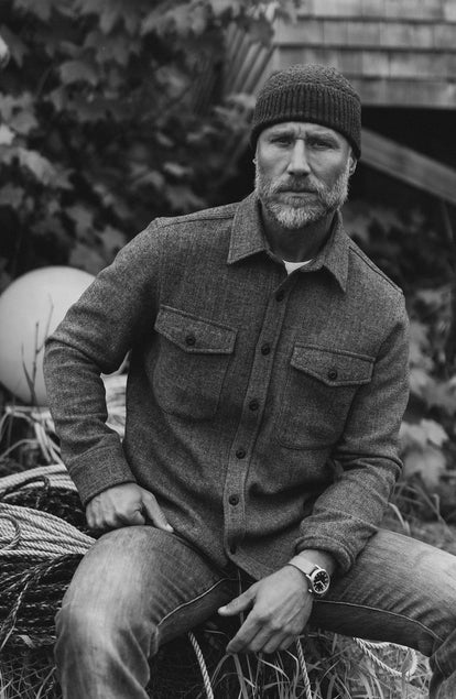 fit model sitting on hay wearing The Textured Knit Beanie in Heather Coal Merino