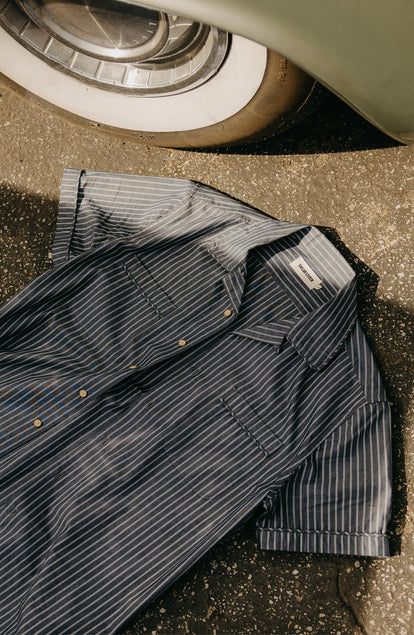 editorial image of The Tulum Shirt in Midnight Stripe on the ground next to a car