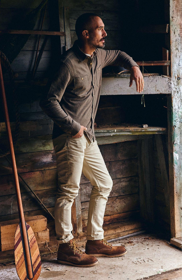 fit model leaning against the wall wearing The Utility Shirt in Fatigue Olive French Terry Twill Knit