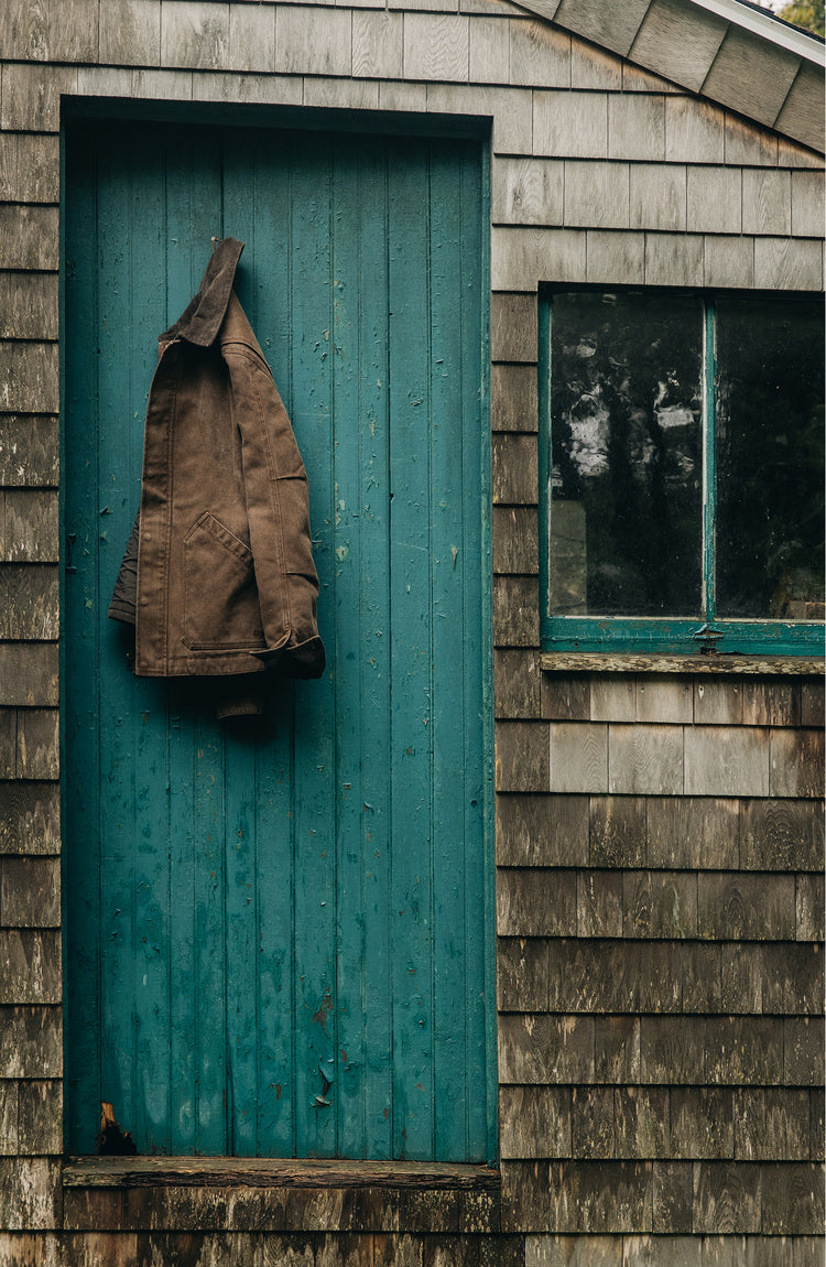 editorial image of The Workhorse Jacket in Aged Penny Chipped Canvas hanging on a door