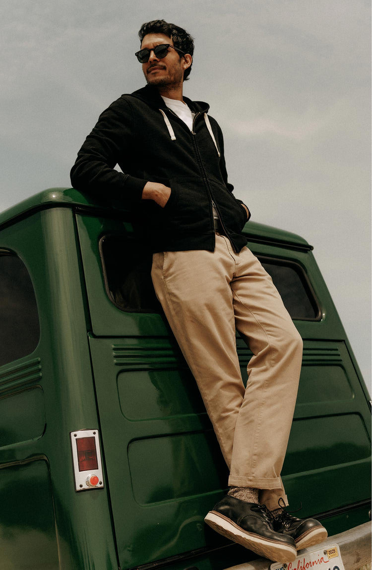 fit model leaning against a car wearing The Apres Zip Hoodie in Black Indigo Terry