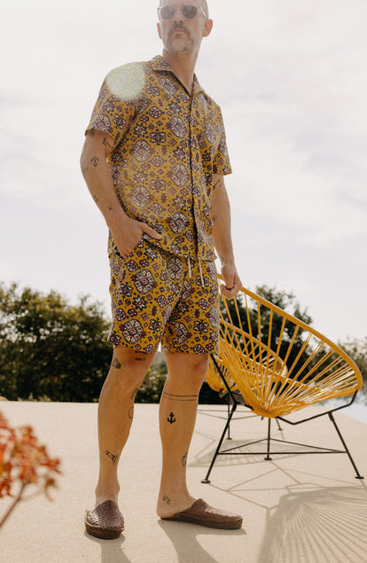 fit model posing next to a chair wearing The Apres Short in Tarnished Gold