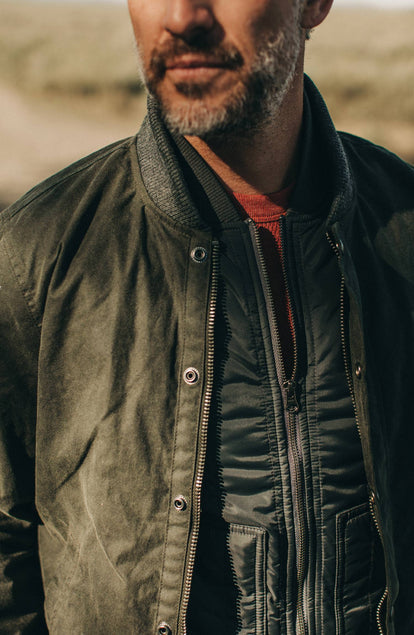 Close up of front of The Bomber Jacket in Waxed Olive showing zipper and layering over vest