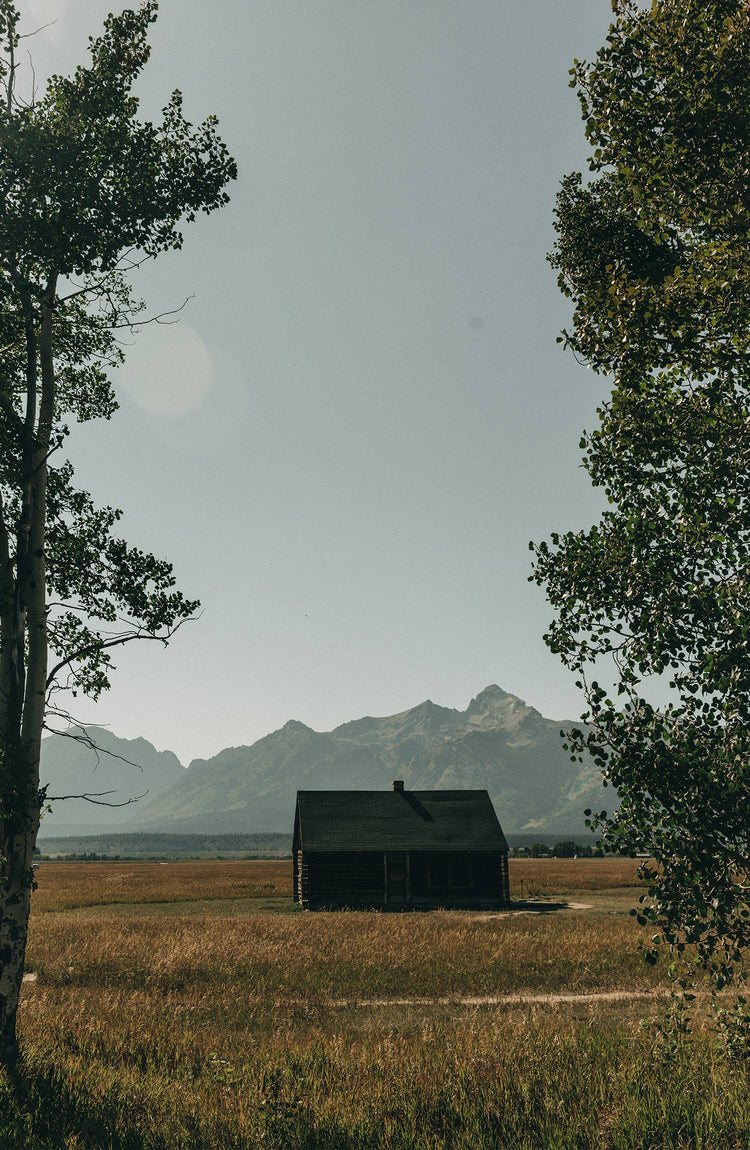 A standalone barn in a meadow in Wyoming with beautiful mountains in the background