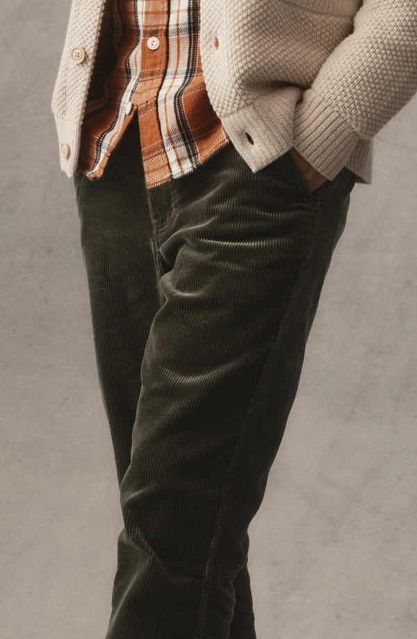 fit model with his hands in his pockets wearing The Carnegie Pant in Smoked Olive Corduroy