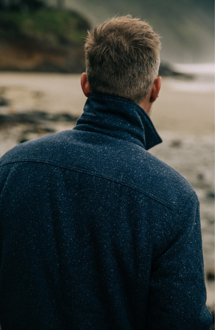 Shot of model from the front sitting down wearing The Chandler Jacket in Navy Donegal