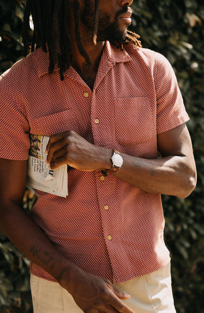 fit model holding a newspaper wearing The Conrad Shirt in Fired Brick Dobby