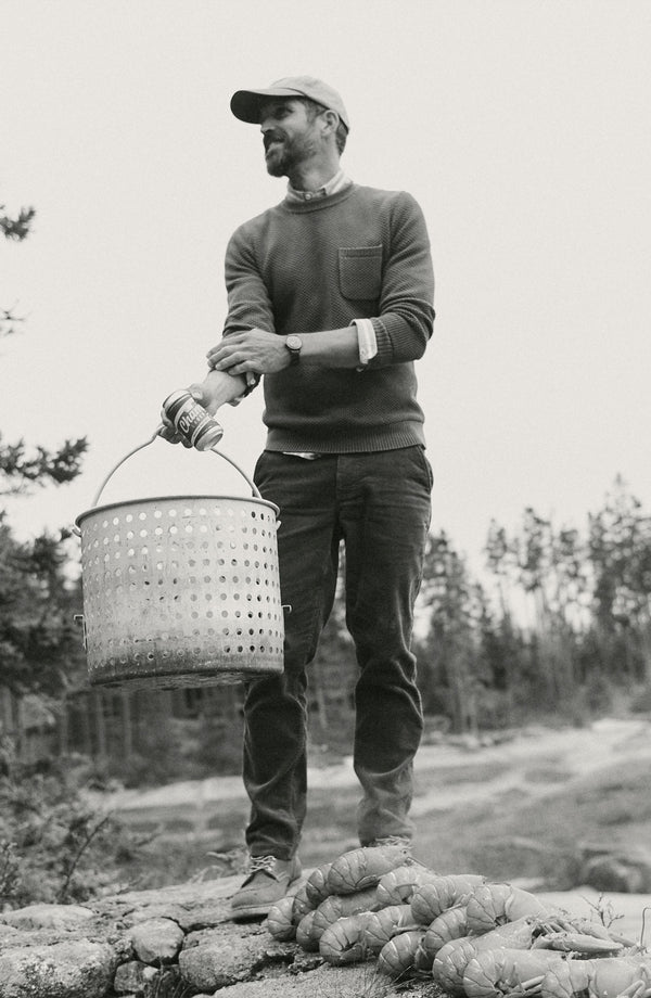 fit model holding a bucket wearing The Crawford Crew Sweater in Faded Spruce
