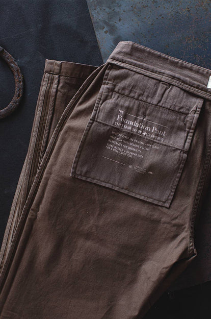 A pair of Foundation Pants folded on a black background, showing the back pocket.