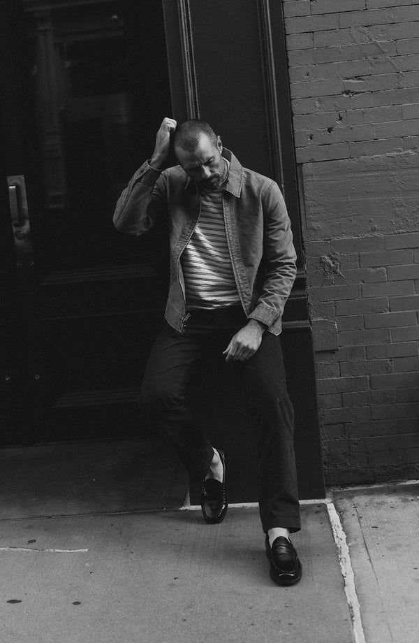 A pair of Foundation Pants folded on a black background, showing the back pocket.