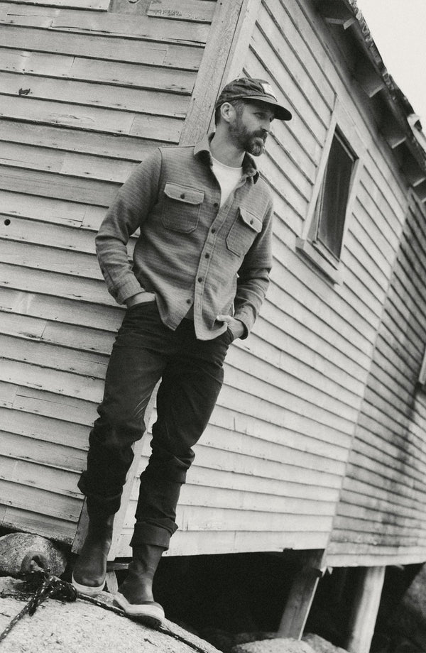 fit model leaning against the wall wearing The Good Acre Chore Pant in Coffee Canvas