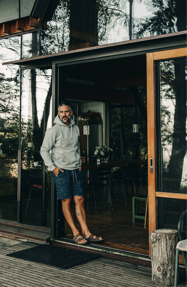 The Heavy Bag Hoodie in Heather Grey Fleece — Model looking out from cabin porch