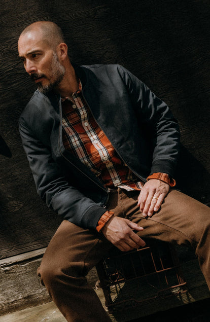 fit model sitting wearing The Insulated Bomber Jacket in Dark Navy Dry Wax