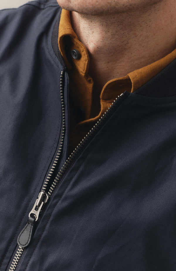 fit model sitting wearing The Insulated Bomber Jacket in Dark Navy Dry Wax