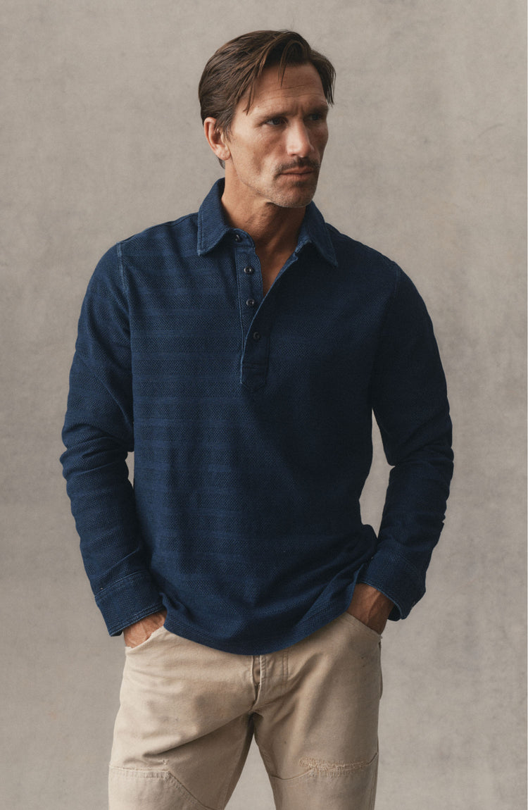 fit model sitting wearing The Long Sleeve Polo in Indigo Knit Stripe