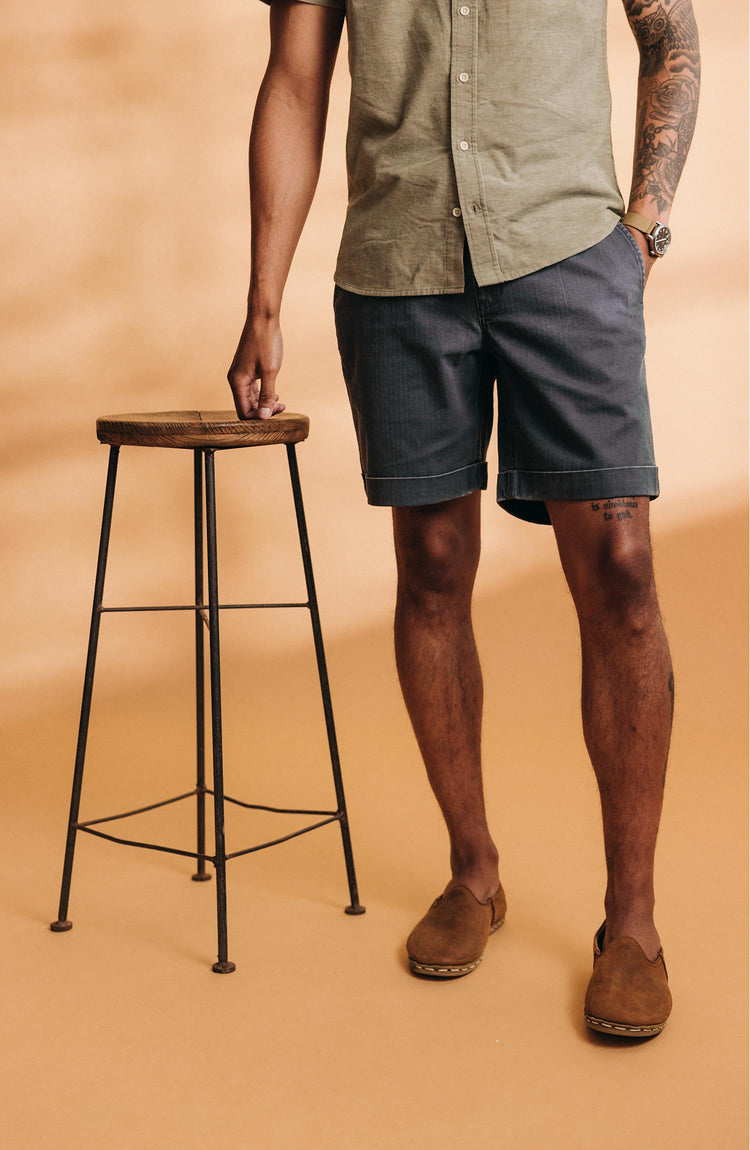 fit model leaning on a stool wearing The Matlow Short in Dark Navy Herringbone