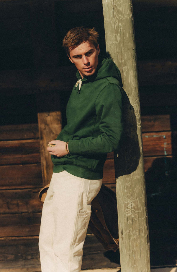fit model leaning against a pole wearing The Shop Hoodie in Ivy French Terry