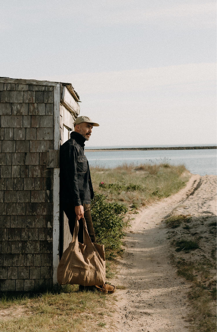 fit model leaning against the wall wearing The Shop Shirt in Rinsed Indigo Selvedge