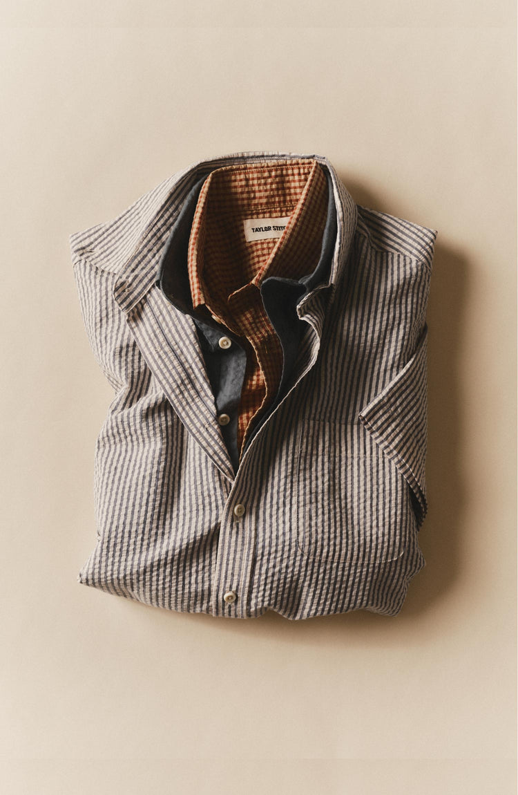 editorial flatlay of various shirts including The Short Sleeve Jack in Steel Blue Stripe Seersucker