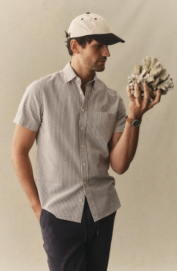 fit model holding a shell wearing The Short Sleeve Jack in Steel Blue Stripe Seersucker