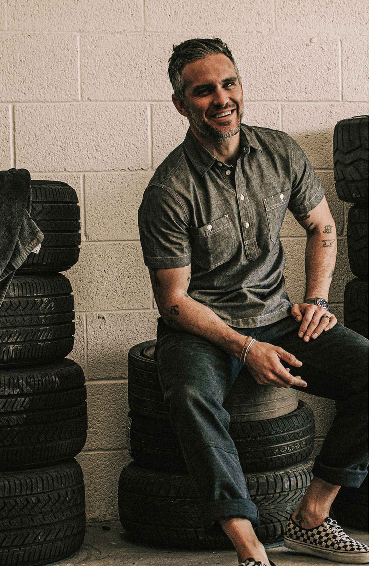 The Short Sleeve Popover in Charcoal Chambray — Model wearing shirt in the garage