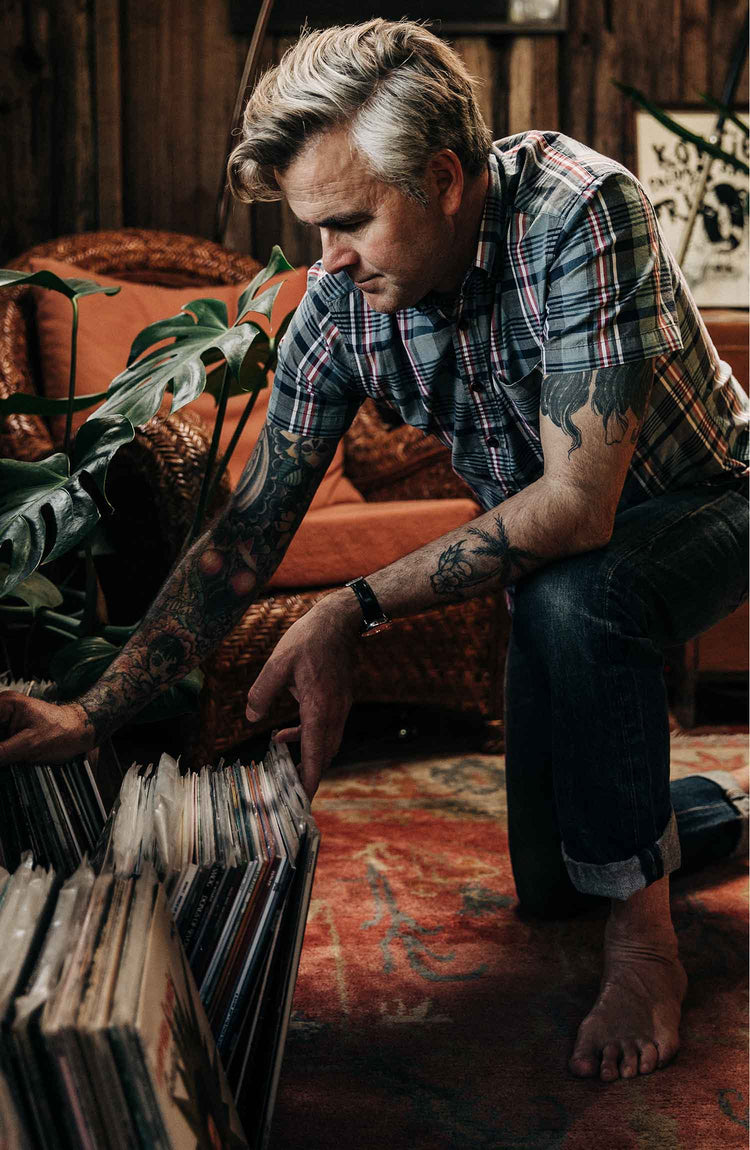 The Short Sleeve Jack in Navy Madras — Model kneeling and stretching the shirt