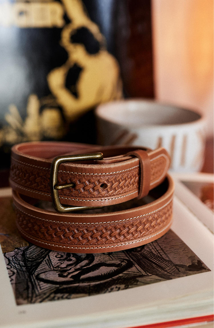 editorial image of The Tooled Belt in Saddle Tan rolled up on a book