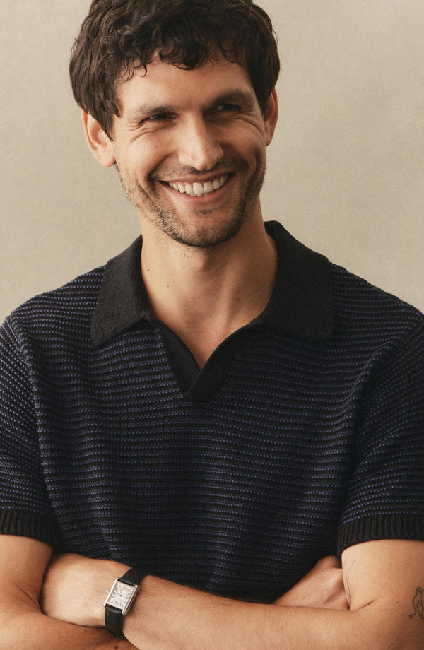 fit model with his arms crossed wearing The Valencia Sweater Polo in Coal Stripe