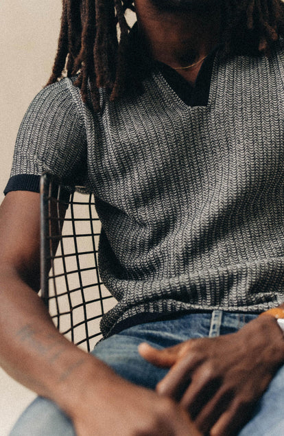 fit model sitting wearing The Valencia Sweater Polo in Coal Scallop